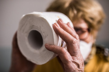 Seniorin mit Mundschutz und Toilettenpapier