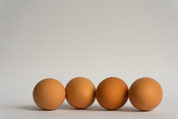 Four fresh brown chicken eggs in a row on grey background. Easter holiday