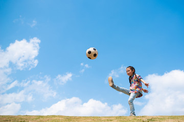 青空の下でサッカーボールを蹴る子供