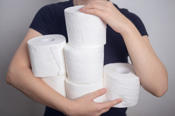 Woman's hands holding many toilet paper rolls. Panic hoarding, buying for the coronavirus quarantine