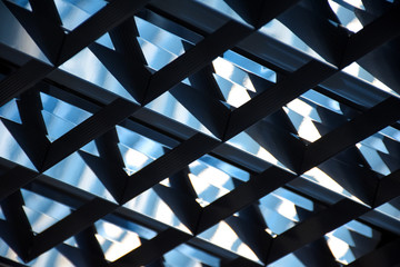 Close-up abstract geometric image of hi-tech luminescent lamp on the ceiling at office premises (selective focus)