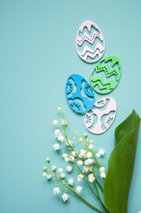 Floral blue background with fresh flowers. Spring greeting card for Easter. A bouquet of lily of the valley and a gift, eggs