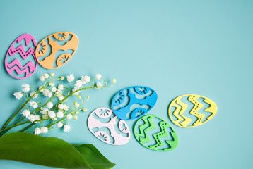 Floral blue background with fresh flowers. Spring greeting card for Easter. A bouquet of lily of the valley and a gift, eggs