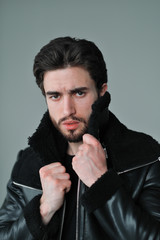 A large portrait of a stylish young man with a beard and dark hair in a black leather jacket