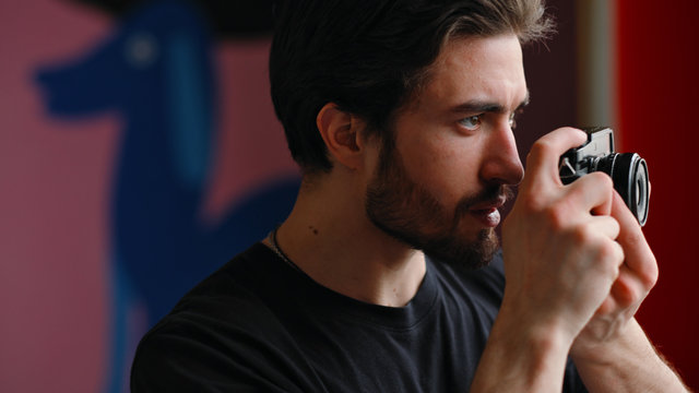 Male photographer uses a mirrorless camera to take a picture.