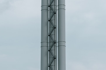 The chimney of a large industrial plant. Tall chimney with a long staircase