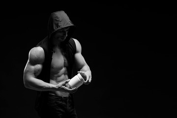 Fototapeta na wymiar Muscular bodybuilder with jar of protein on a dark background. Sports nutrition. Bodybuilding nutrition supplements, sport, workout, healthy lifestyle concept.
