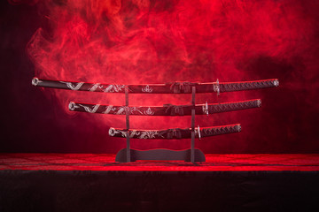 Three swords on stand, red smoke behind