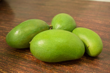 Organic Young Green Mangoes on Wooden Table sour fruits.