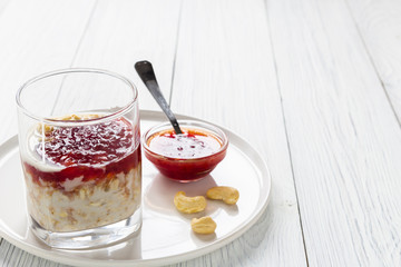 Oatmeal with milk and strawberry jam in glass on white wooden table. healthy organic food. breakfast. copy space
