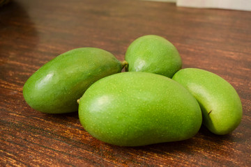 Organic Young Green Mangoes on Wooden Table sour fruits.