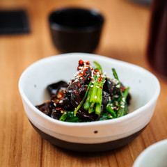 Closeup on wood ear mushrooms with spinach and species in small white bowl on the wooden table