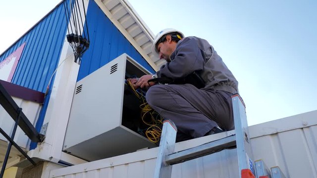 Technician makes repairs in the technical box of the Internet provider