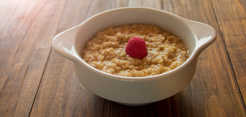 A plate of the fresh beautiful porridge on a wooden background.
