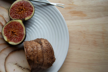 On a white plate meat roll with chopped ripe figs. The roll is cut into round pieces
