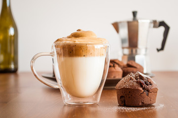 Korean coffee (Dalonga Caffee) and chocolate muffin on a wooden table. In the background an Italian coffee shop and a bottle of wine. Picture taken in Germany.
