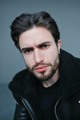 Fototapeta premium A large portrait of a stylish young man with a beard and dark hair in a black leather jacket