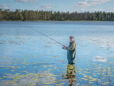 Karelia, Vodlozero - 29.07.2019: Young man fishing with spinning in lake. Ecotourism, visiting fragile, pristine, undisturbed natural areas. Active holidays in Karelia. Portrait