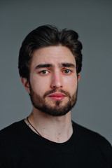 Fototapeta premium Close-up portrait of a young stylish man with a beard and dark hair in a black T-shirt 
