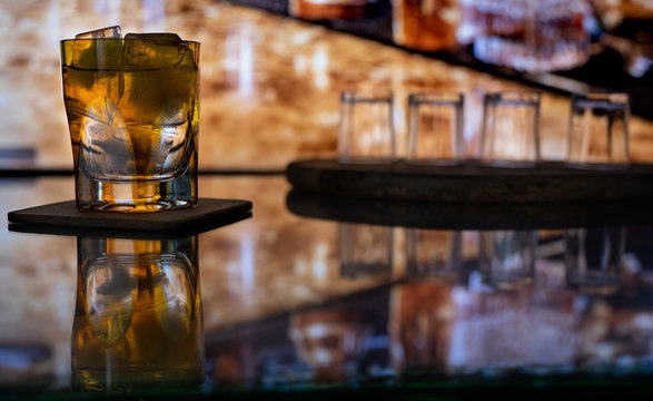 Whiskey with ice or brandy in a glass on a bar tap in a traditional style pub. Whiskey with ice in a glass.