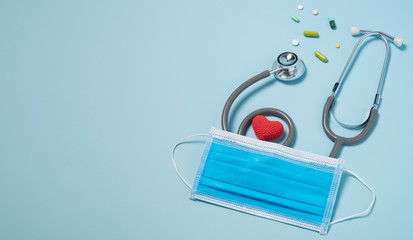 medical equipment stethoscope with red heart and drug, surgical mask on blue copy space background.