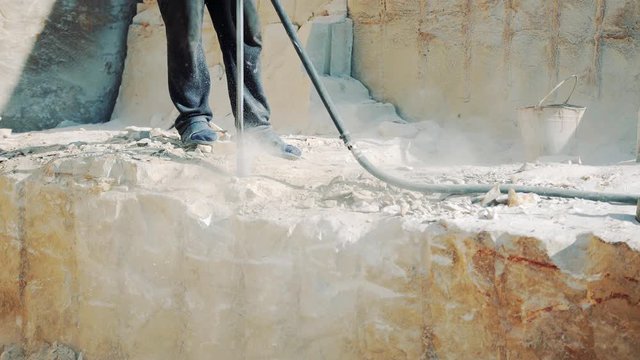 Drilling holes in the stone with a jackhammer. Sandstone mining in the quarry. Close-up.