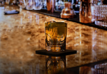 Whiskey with ice or brandy in a glass on a bar tap in a traditional style pub. Whiskey with ice in a glass.