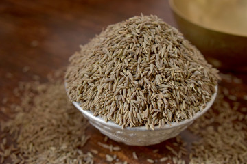 Dried Cumin Seeds  in a Silver bowl on wooden old Table. rustic style 