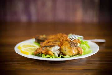 fried hake fish in batter with lettuce and lemon in a plate