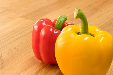 Yellow and red bell peppers on wooden chopping board. Close up shot.