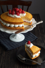 Sliced Victoria Sponge Sandwich Cake with Layers of Whipped Cream, Raspberry Jam, and Fresh Raspberries on Cake Stand