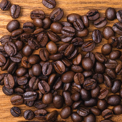 Freshly roasted coffee beans. Background of roasted coffee beans scattered on a wooden table.
