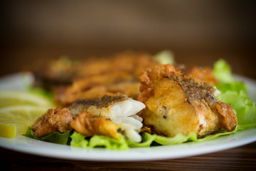 fried hake fish in batter with lettuce and lemon in a plate