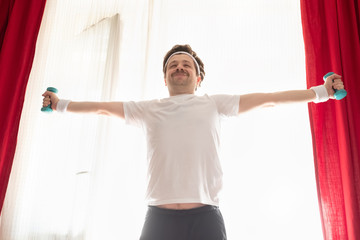Funny mature man exercising at home holding weights