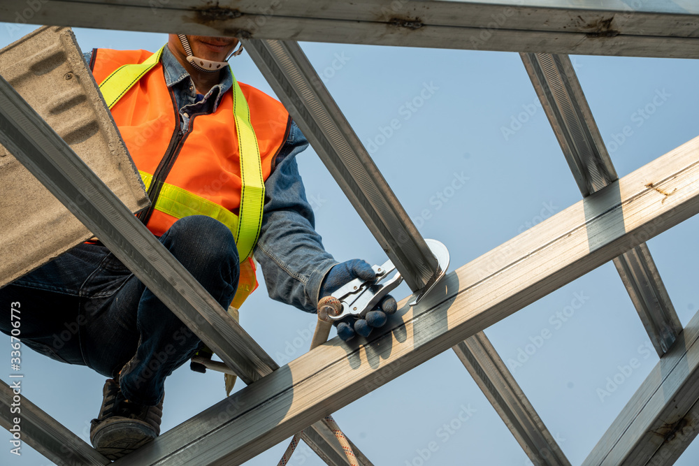 Poster construction worker wearing safety harness and safety line working at high place are installing new 