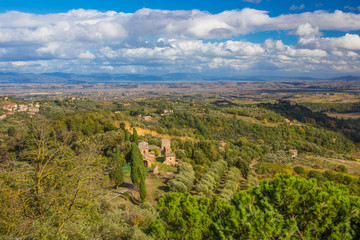 Fototapeta na wymiar Autumn landscape in Tuscany, Italy. Beautiful view with a house in the D'Orcia Valley, surrounded by green trees.