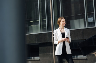 Photo of smiling businesswoman in white blazer , talking on the phone