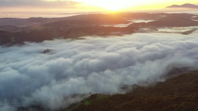 A beautiful sunrise illuminates fog as it rolls through valleys in Northern California. Just west of these tranquil hills and valleys is the densely populated area of San Francisco Bay.