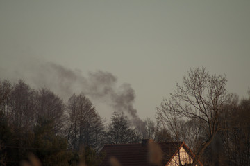 Fototapeta na wymiar Czarny dym wydobywający się z komina domu świadczący o spalaniu śmieci.