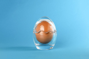 Egg in egg shape glass container protection shell on blue background safety security