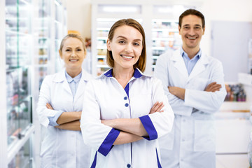 Cheerful three pharmacists waiting for customers in a drugstore