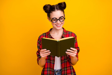 Photo of pretty crazy lady two buns hold open book diligent student interesting story novel wear geek vision specs casual checkered shirt isolated yellow color background