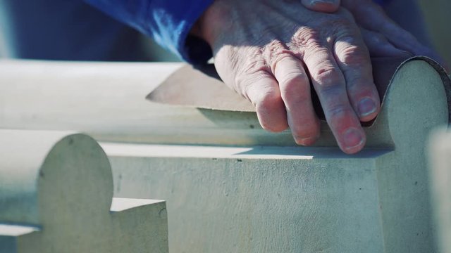 A man polishes sandstone with sandpaper. Production of decorative products and sculptures made of stone. Close-up.