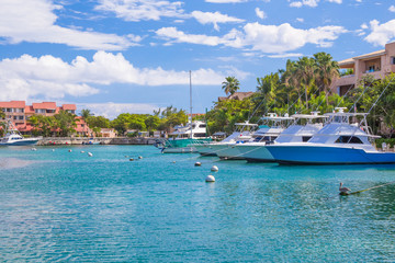 Fototapeta na wymiar Harbor / marina in Puerto Aventuras with boats on a sunny day. The beautiful and popular coastal city in Riviera Maya, Mexico.