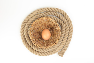 Egg in straw basket jute rope circle around on white background