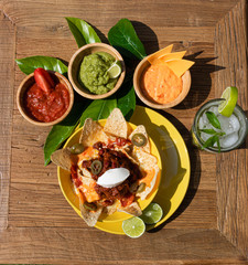plato de nachos con salsas en fondo de madera