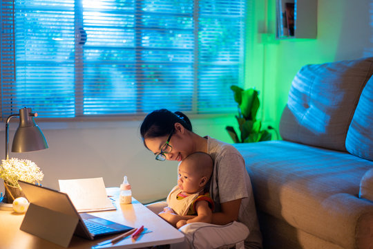 Asian Mother And Child Sitting And Working At Home At Night