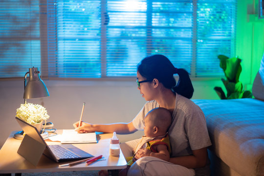 Asian Mother And Child Sitting And Working At Home At Night