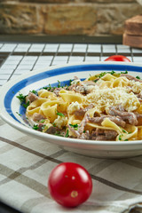 Italian fettuccine pasta in cheese sauce with parmesan, chicken and ham, herbs in white ceramic bowl on white background.