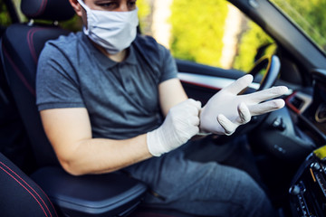 Man with protective mask and gloves driving a car. Infection prevention and control of epidemic. World pandemic. Stay safe.